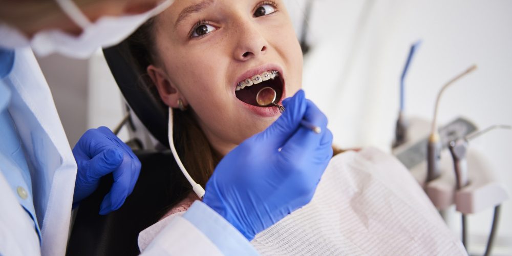 Part of orthodontist examining child's teeth in dentist's office